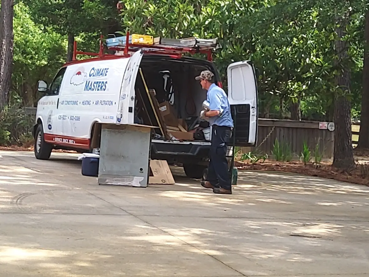 A Climate Masters, Inc. technician unloading equipment from the company van in a Baldwin County driveway