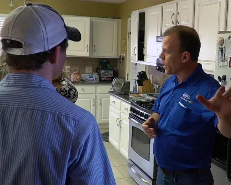 Richard Morrison and HVAC tech speaking with home owner in kitchen