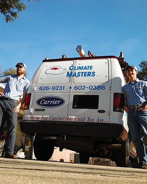 Two Climate Masters technicians standing at the back of a branded Climate Masters service van parked outdoors under a clear blue sky