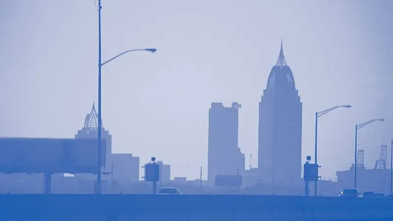 The downtown Mobile, Alabama skyline on a hazy day, seen from the elevated Bayway causeway with its streetlights and traffic in the foreground