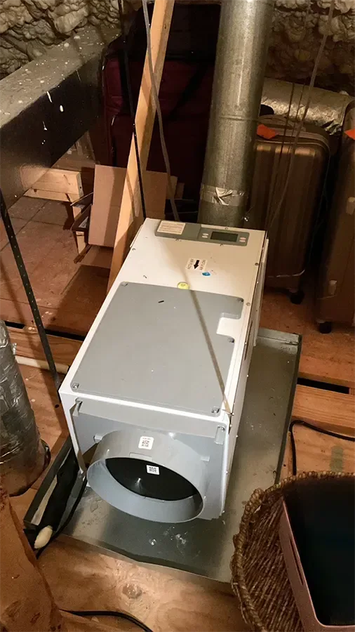 A horizontal whole-house dehumidifier installed in a secondary drain pan on attic subflooring in Spanish Fort