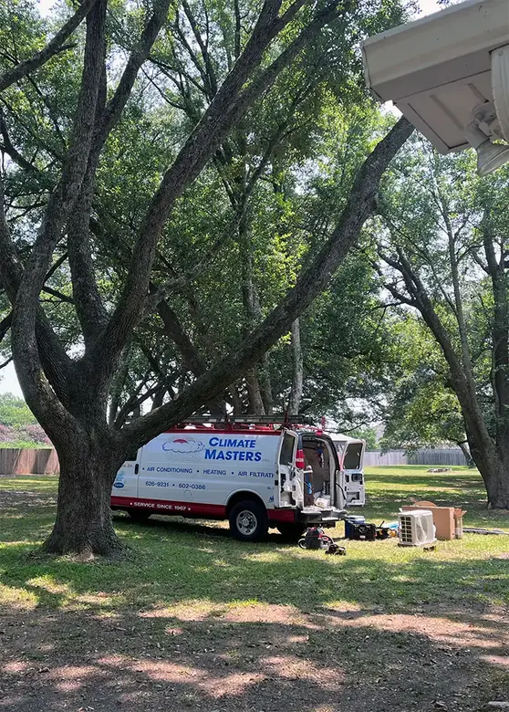 A Climate Masters service van parked on a shaded lawn with tools and equipment unloaded beside it