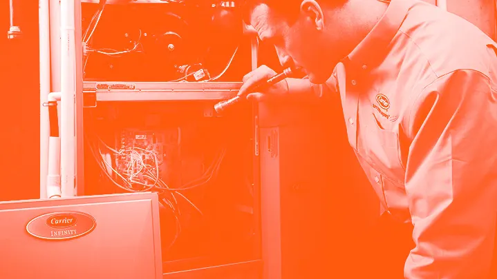 Carrier HVAC technician repairing furnace in monotone orange | Climate Masters INC | Furnace Repair