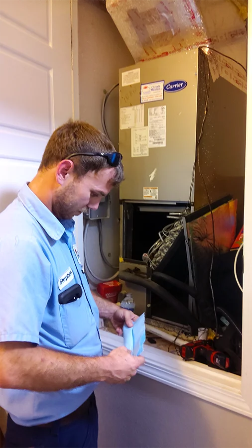 Technician inspecting a central air conditioning unit | HVAC Contractors | Climate Masters Inc.
