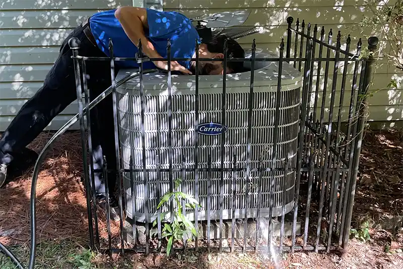 Technician inspecting and looking inside a outdoor air conditioning unit | HVAC Contractors | Climate Masters Inc.